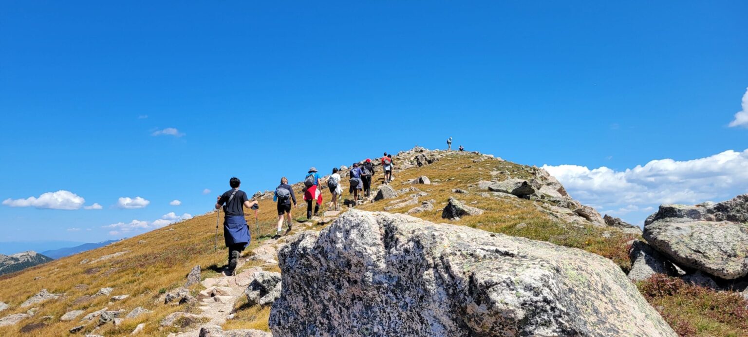 Students backpack along the mountain side as part of the wilderness program at UWC-USA.