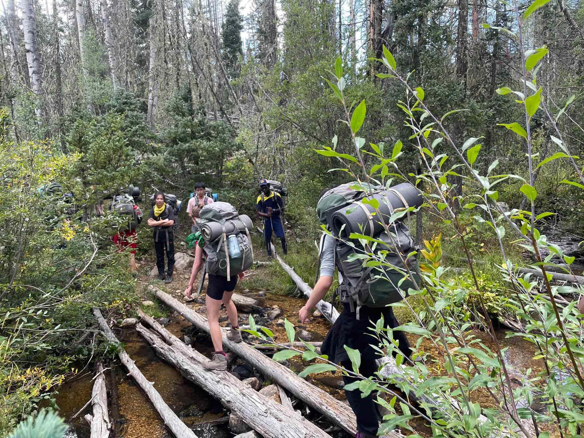 Students walk on logs in the Pecos wilderness as part of the UWC-USA wilderness program.