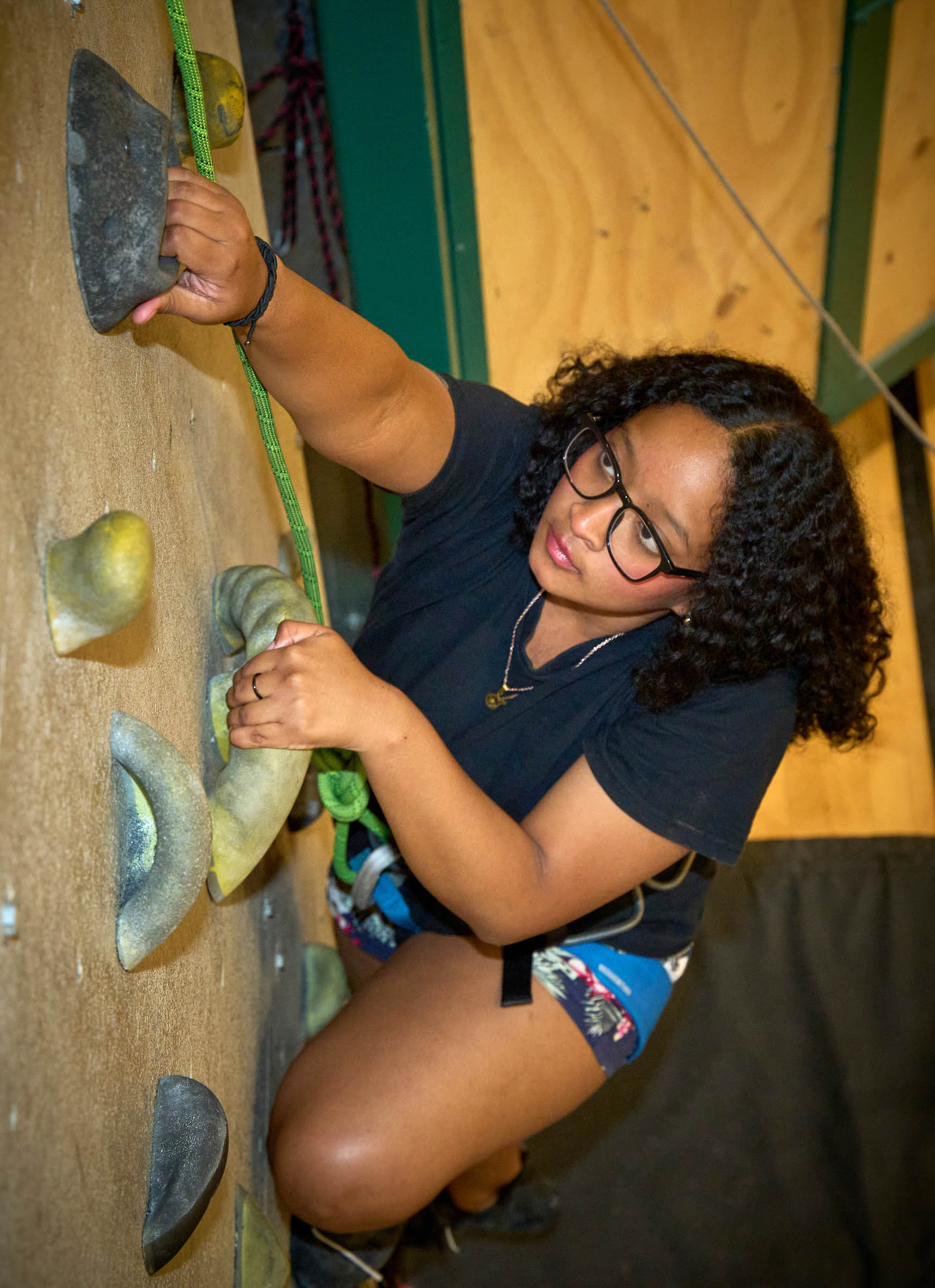 Student rock climbing on the rock climbing wall at the Edith Lansing Field House on UWC-USA Campus.