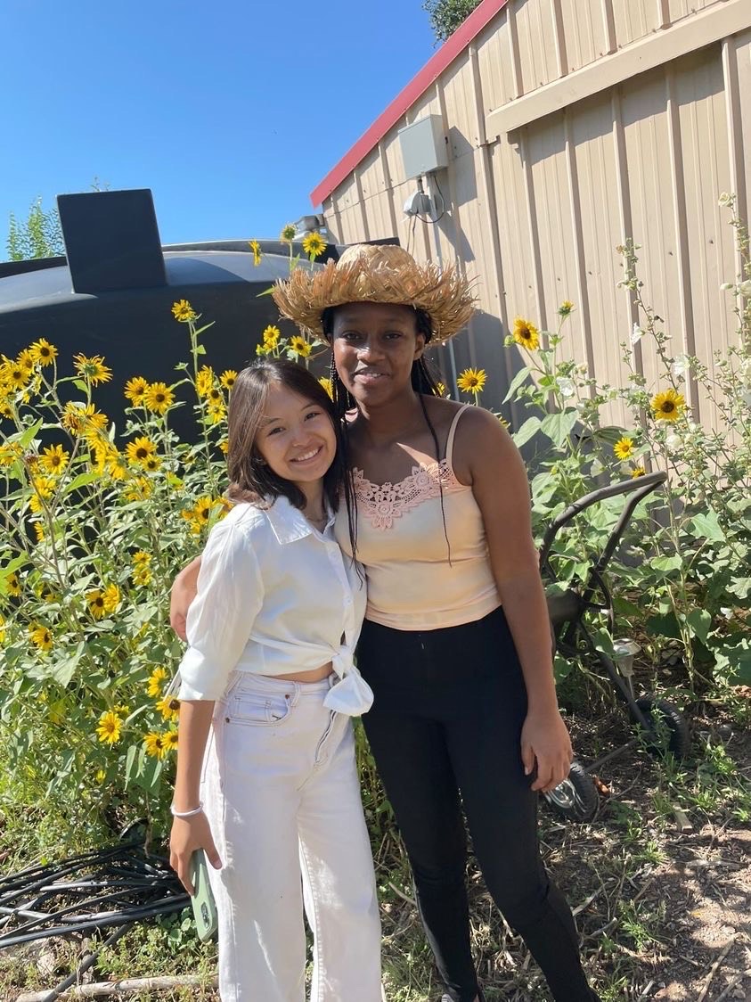Two diverse students share a moment in UWC-USA’s sunflower garden at the Farm, reflecting global friendship and commitment to sustainability.