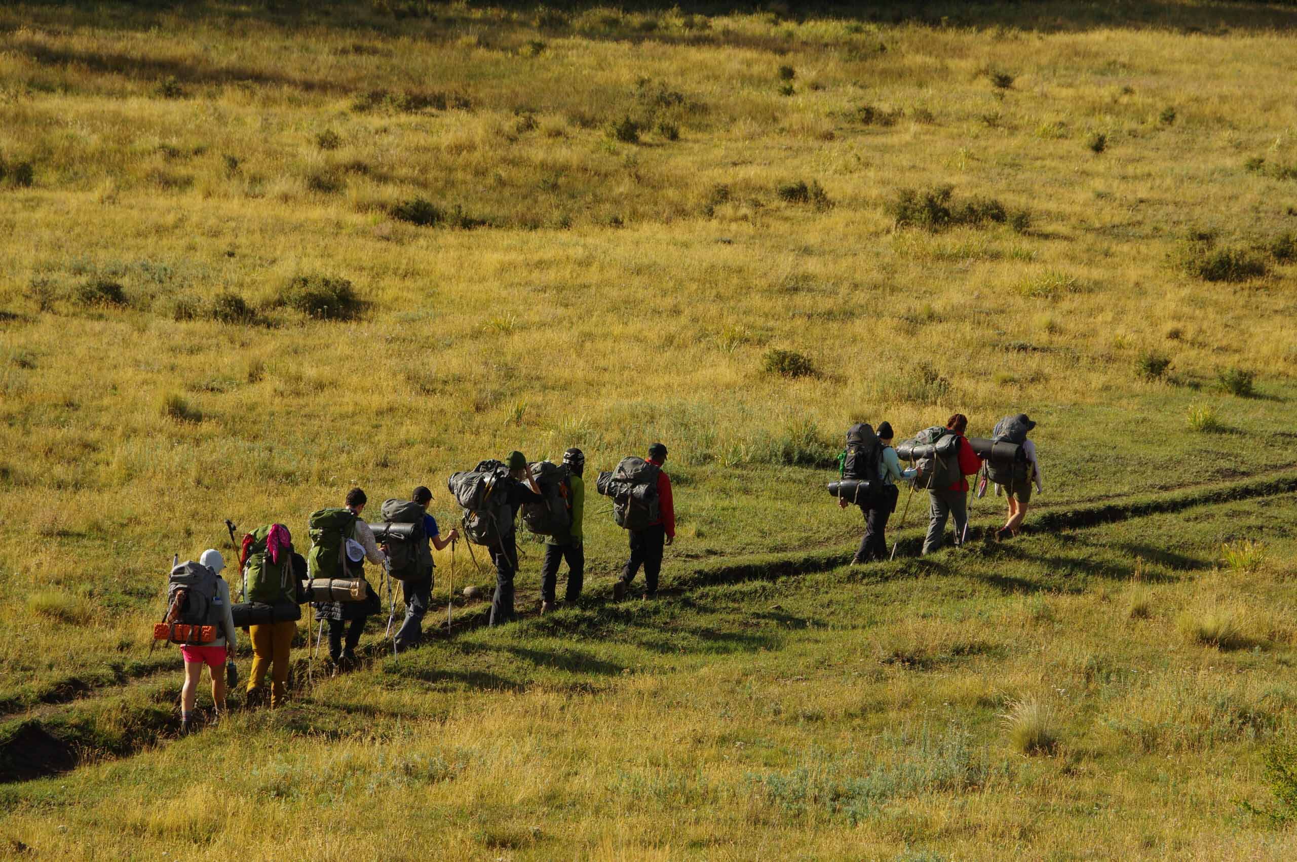 Students from diverse backgrounds hike together on New Mexico trails, embracing wilderness and teamwork at UWC-USA.