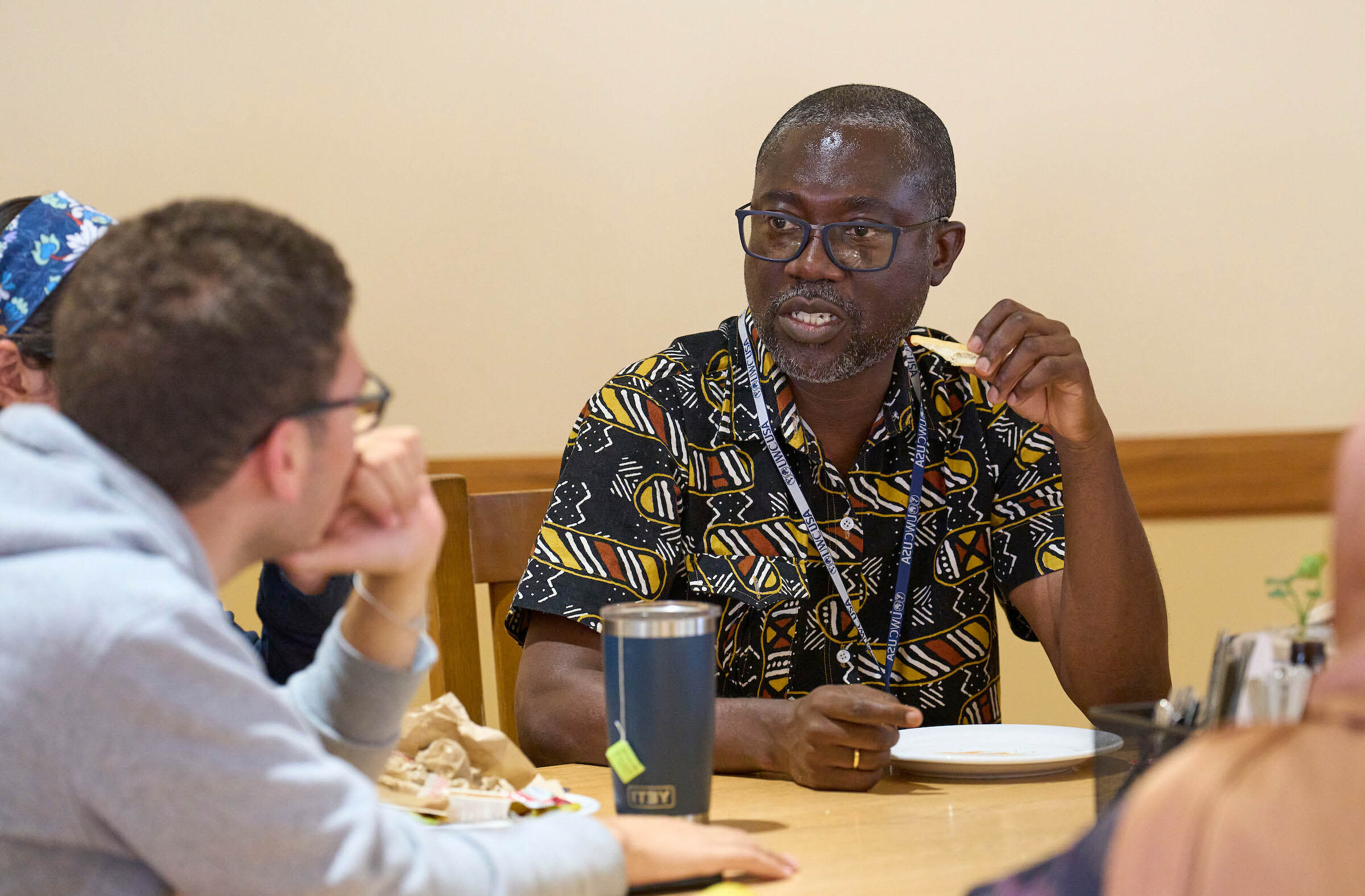 Students and IB teacher from diverse backgrounds engage in thoughtful discussion over a meal, reflecting UWC-USA’s global community and values.