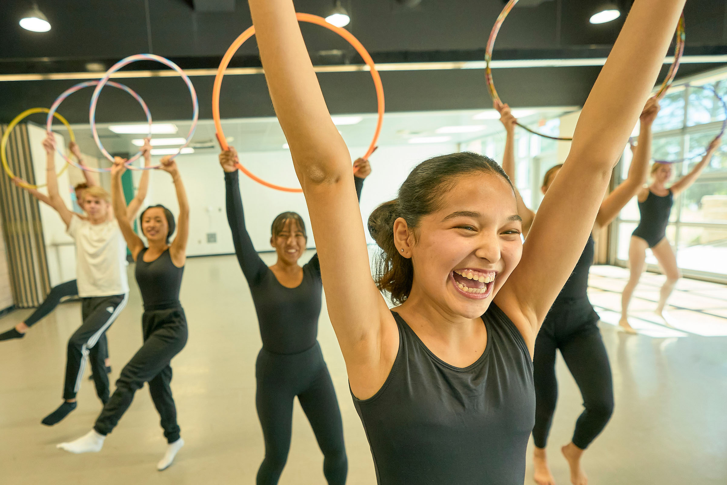 Diverse UWC-USA students joyfully practice hoop dance in a bright dance studio, reflecting creativity, global unity, and community spirit.