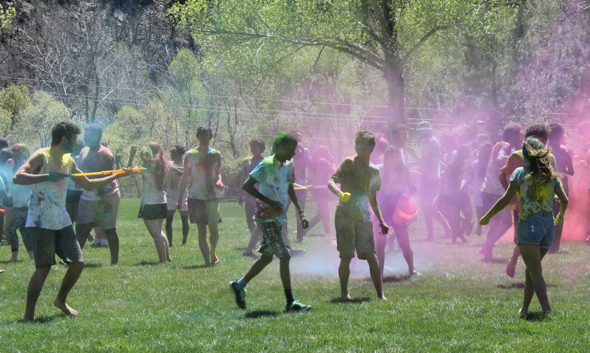 Diverse students celebrate Holi on a sunny field, sharing culture and community in UWC-USA’s vibrant global environment.