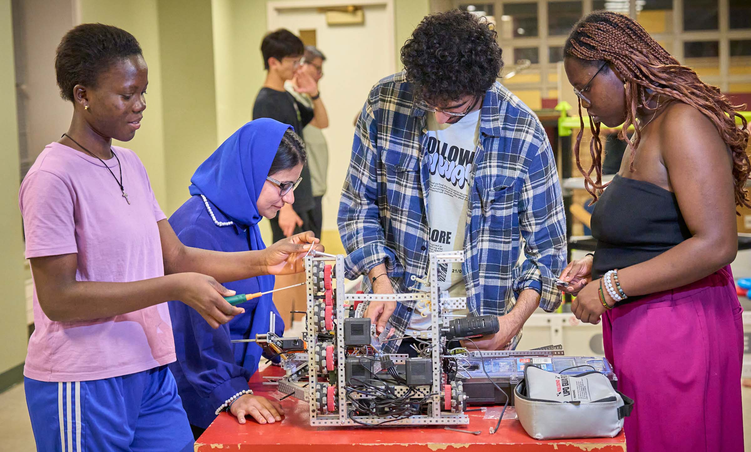 Diverse UWC-USA students collaborate on robotics in a hands-on academic setting, reflecting innovation and global teamwork.
