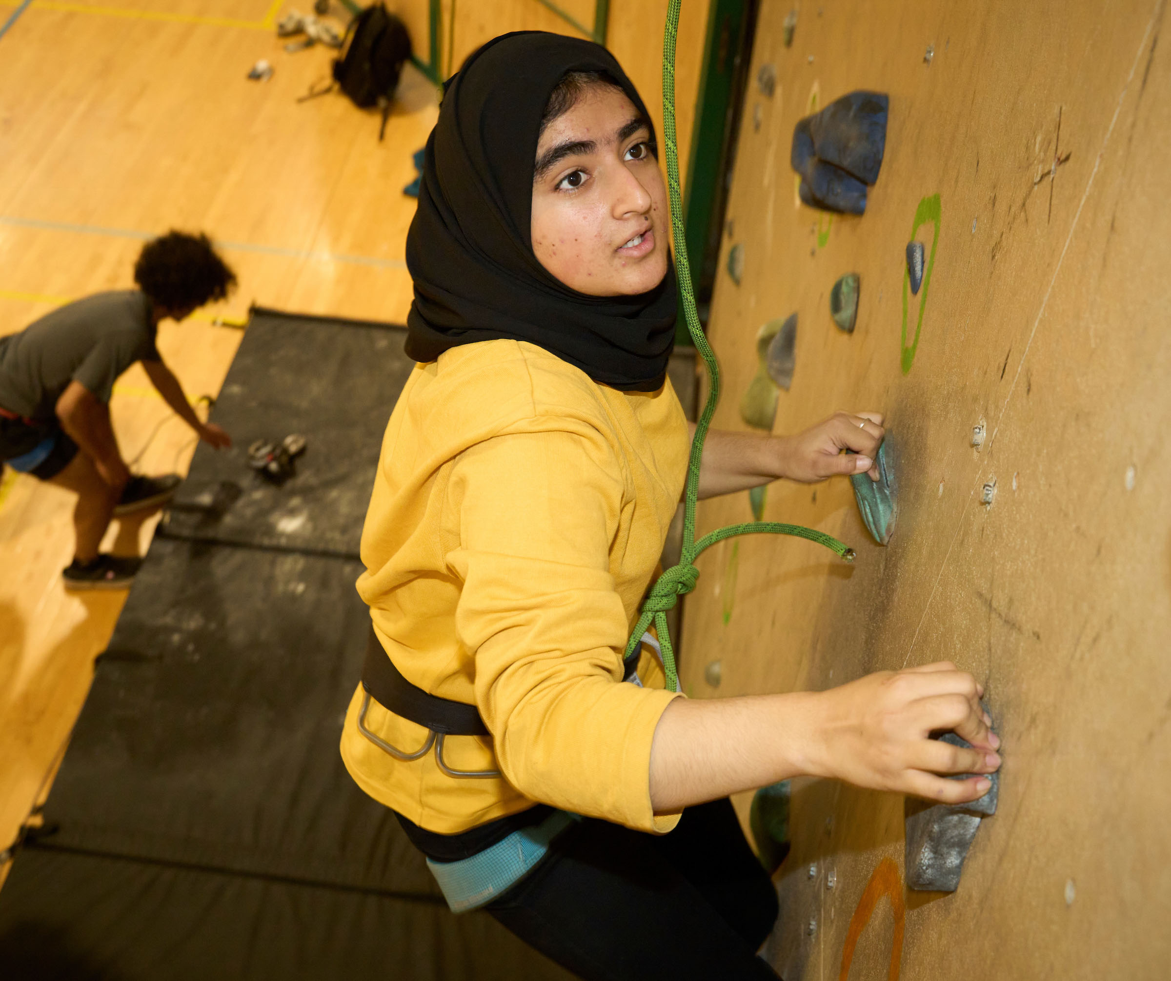 Student climbs the UWC-USA rock wall, reflecting co-curricular activities.