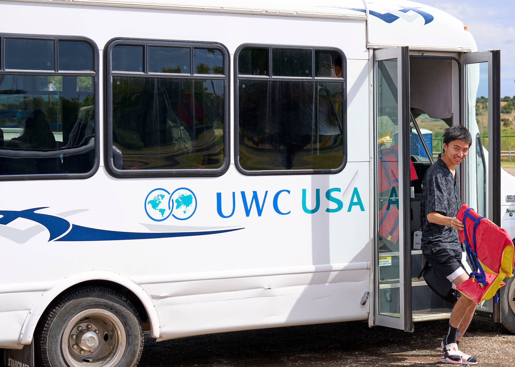 A UWC-USA student smiling as he exits the shuttle bus, embodying global community and joyful engagement.