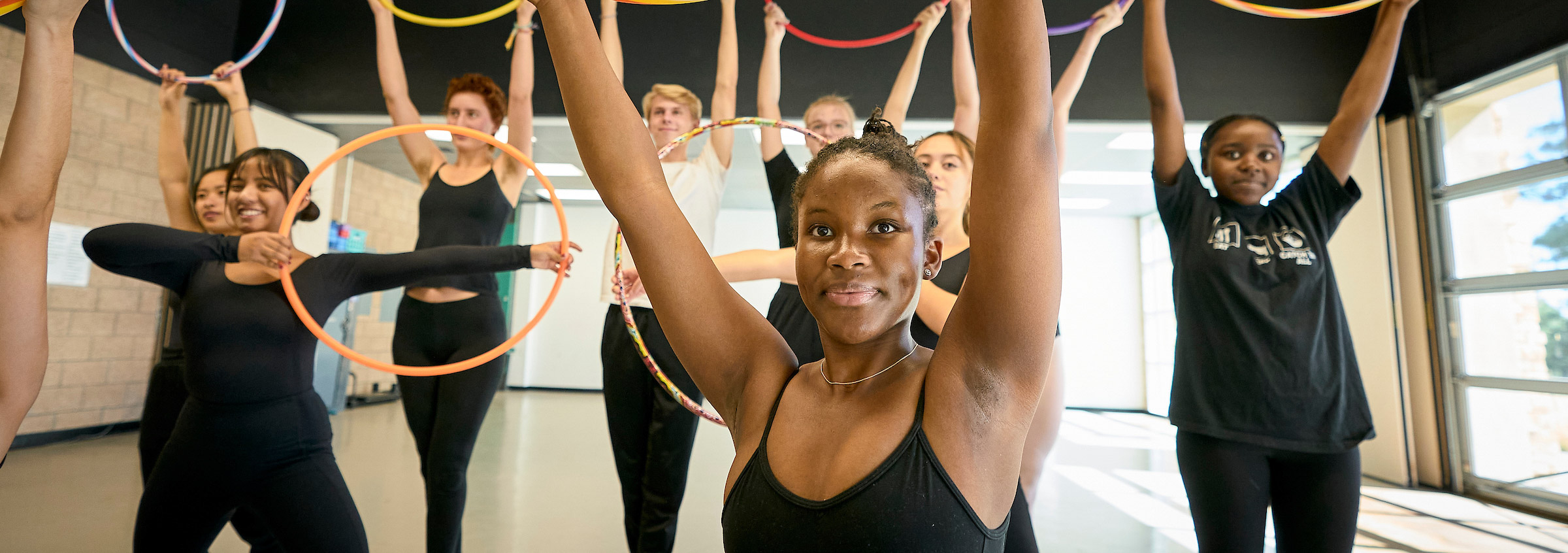 Diverse students practice with hula hoops in a sunny UWC-USA dance studio, reflecting community, energy, and joyful engagement.