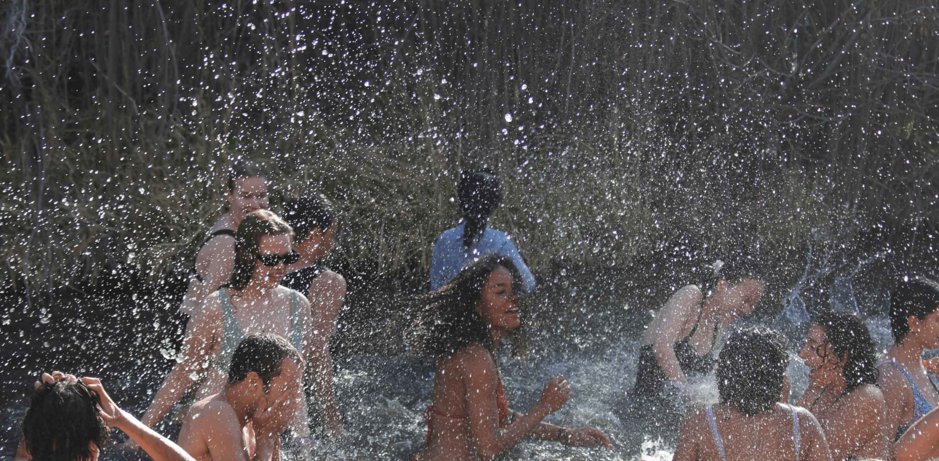 Students from diverse backgrounds play together in water, sharing joy and connection at UWC-USA’s unique wilderness setting.