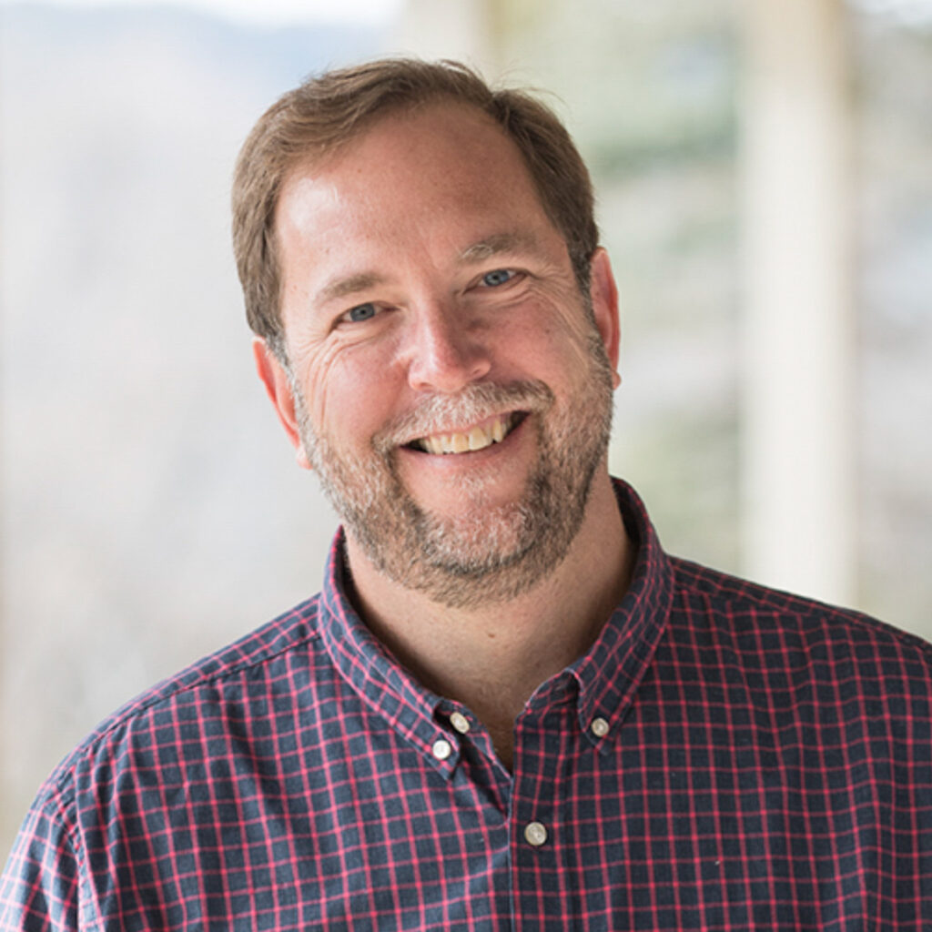 Carl-Martin Nelson smiles while holding papers outdoors on campus, fostering a welcoming global community at UWC-USA.