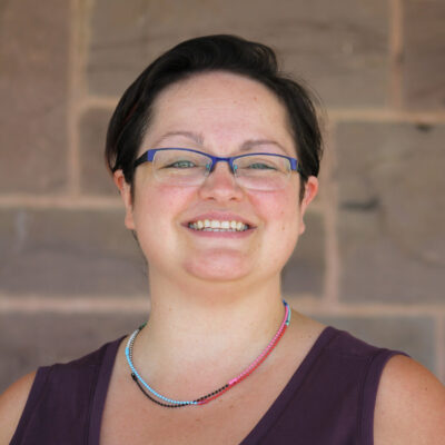 Erin Gilland stands before a stone wall, reflecting UWC-USA’s commitment to diversity and global community.