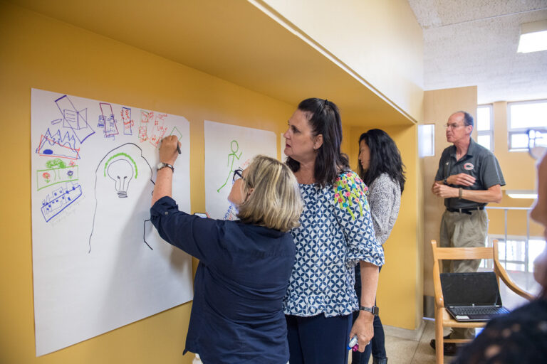 Diverse adults collaborate on creative projects during Winter IB Workshops, fostering global citizenship and community in a vibrant space.