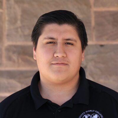 Jordan Salgado, UWC-USA Security team member, stands against a brick wall, reflecting our diverse and welcoming campus community.