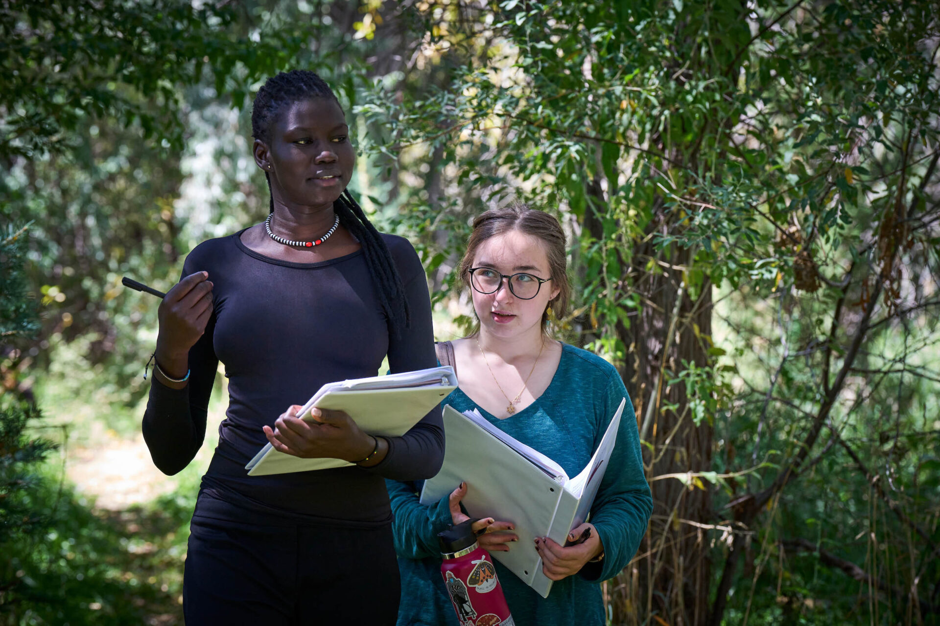 Two students walk in the forests of UWC-USA campus for outdoor experiential learning.