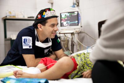 A caring healthcare worker connects with a young patient, reflecting compassionate service and a commitment to global well-being.
