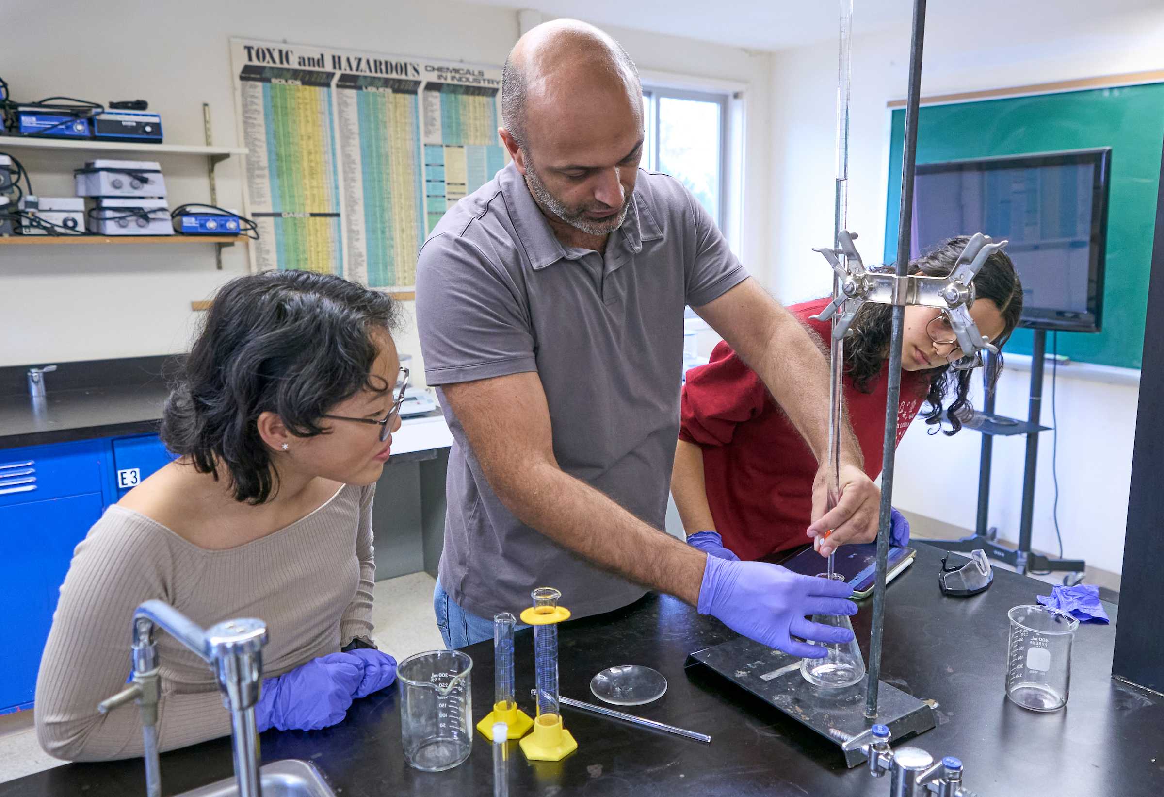 UWC-USA IB teacher assisting students in the chemistry lab.