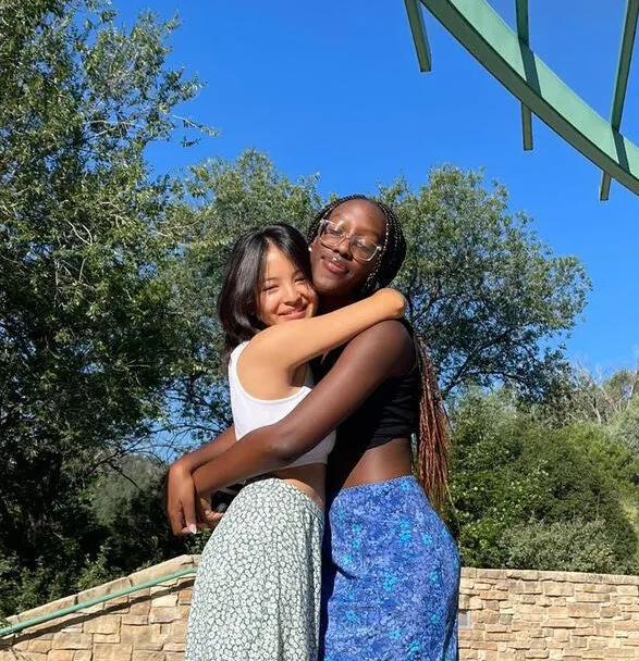 Two diverse UWC-USA students share a joyful hug outdoors, reflecting global friendship and academic excellence on campus.