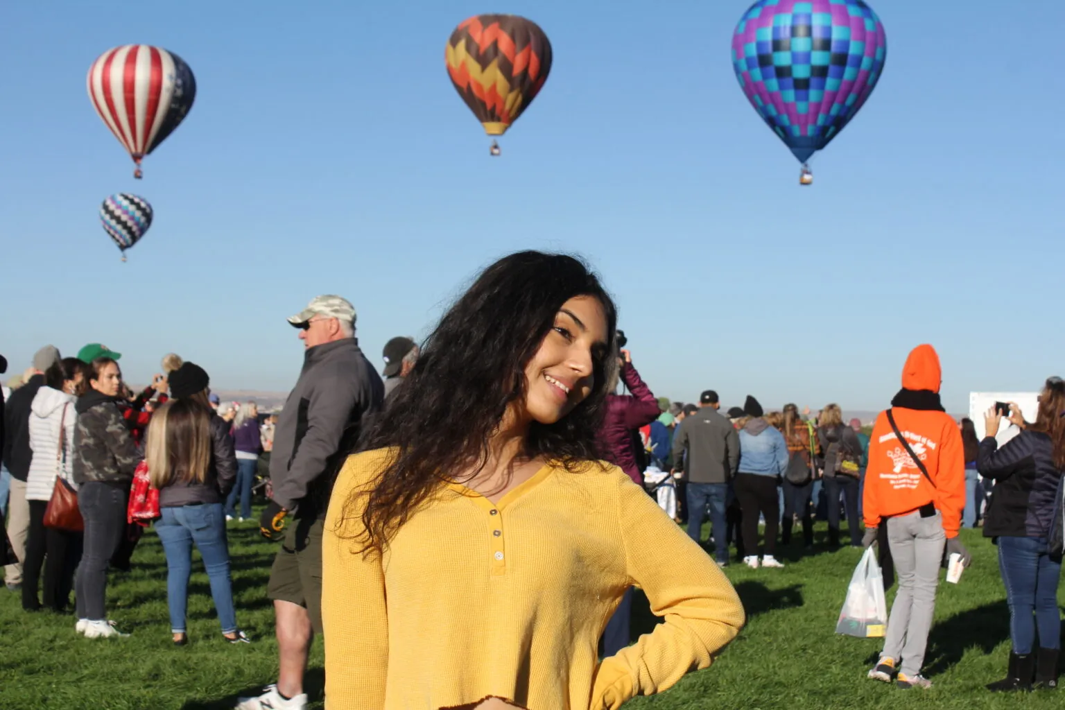 Student enjoys the Balloon Fiesta gathering beneath vibrant hot air balloons, celebrating New Mexico community.