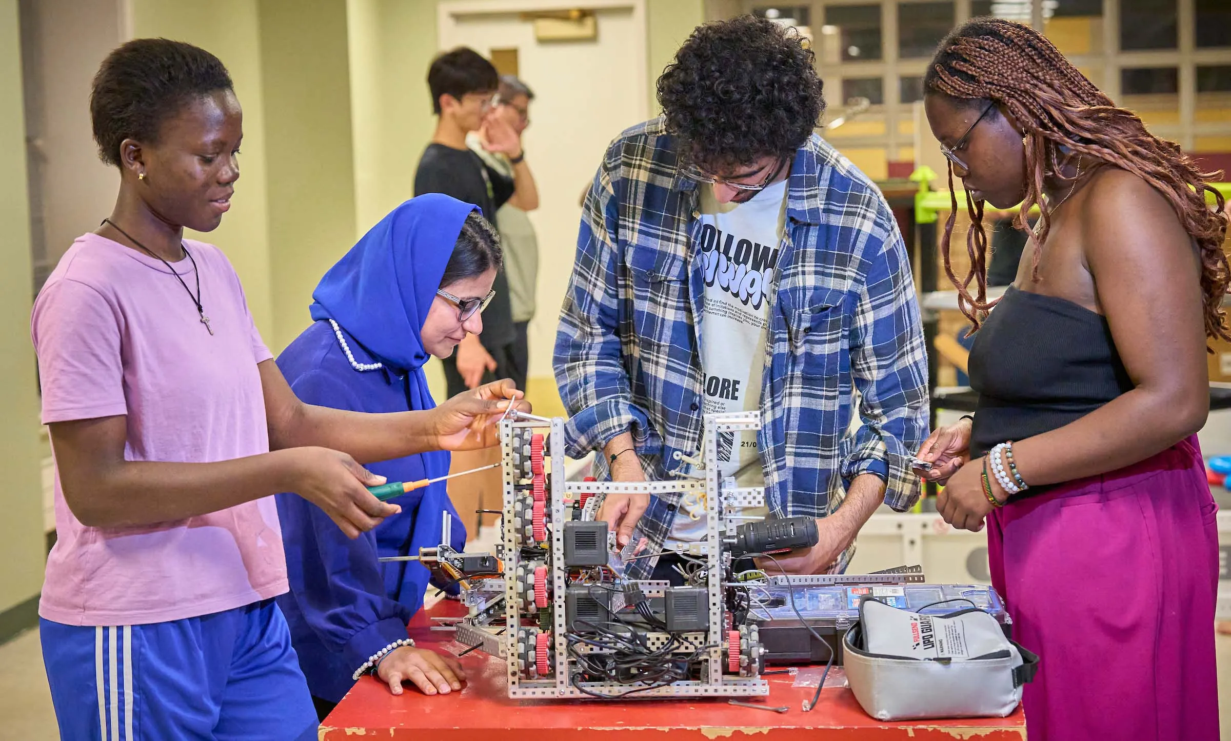 Diverse UWC-USA students collaborate on robotics in a hands-on academic setting, reflecting innovation and global teamwork.