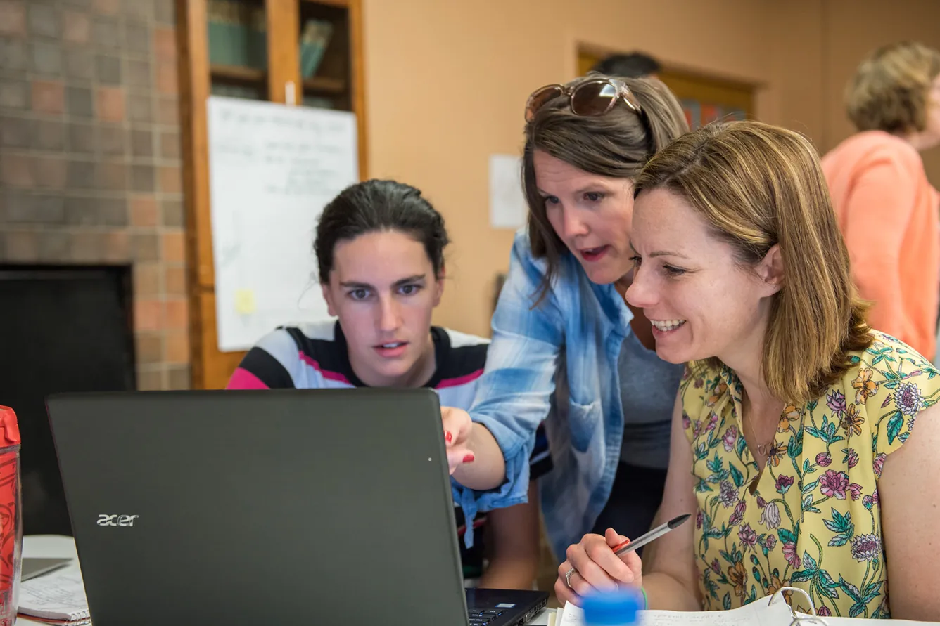 Diverse students collaborate around a laptop during Winter IB Workshops, reflecting IB academics and UWC-USA’s global community.