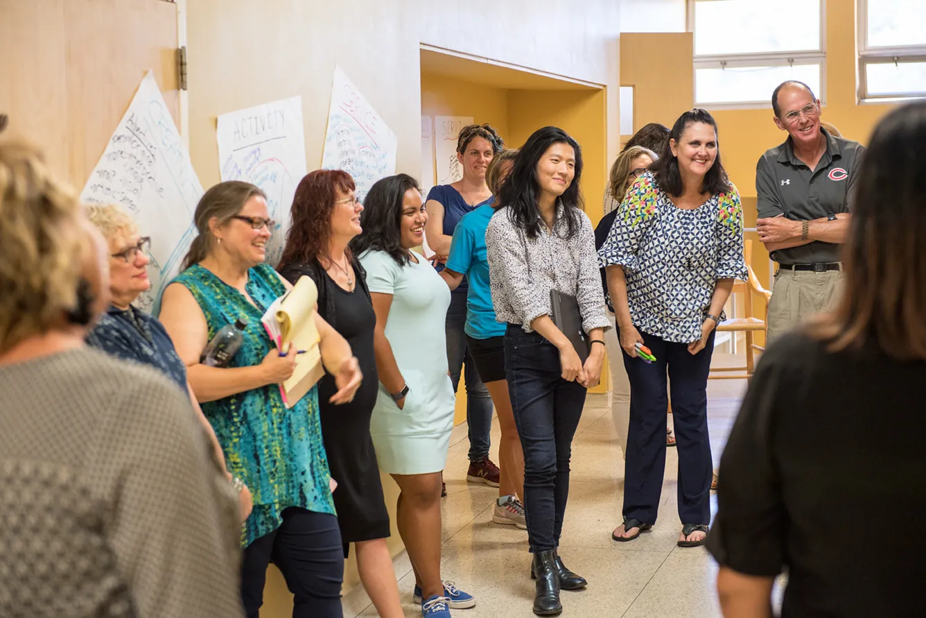 Diverse UWC-USA IB Workshop students engaging collaboratively amidst posters reflecting global learning and service.