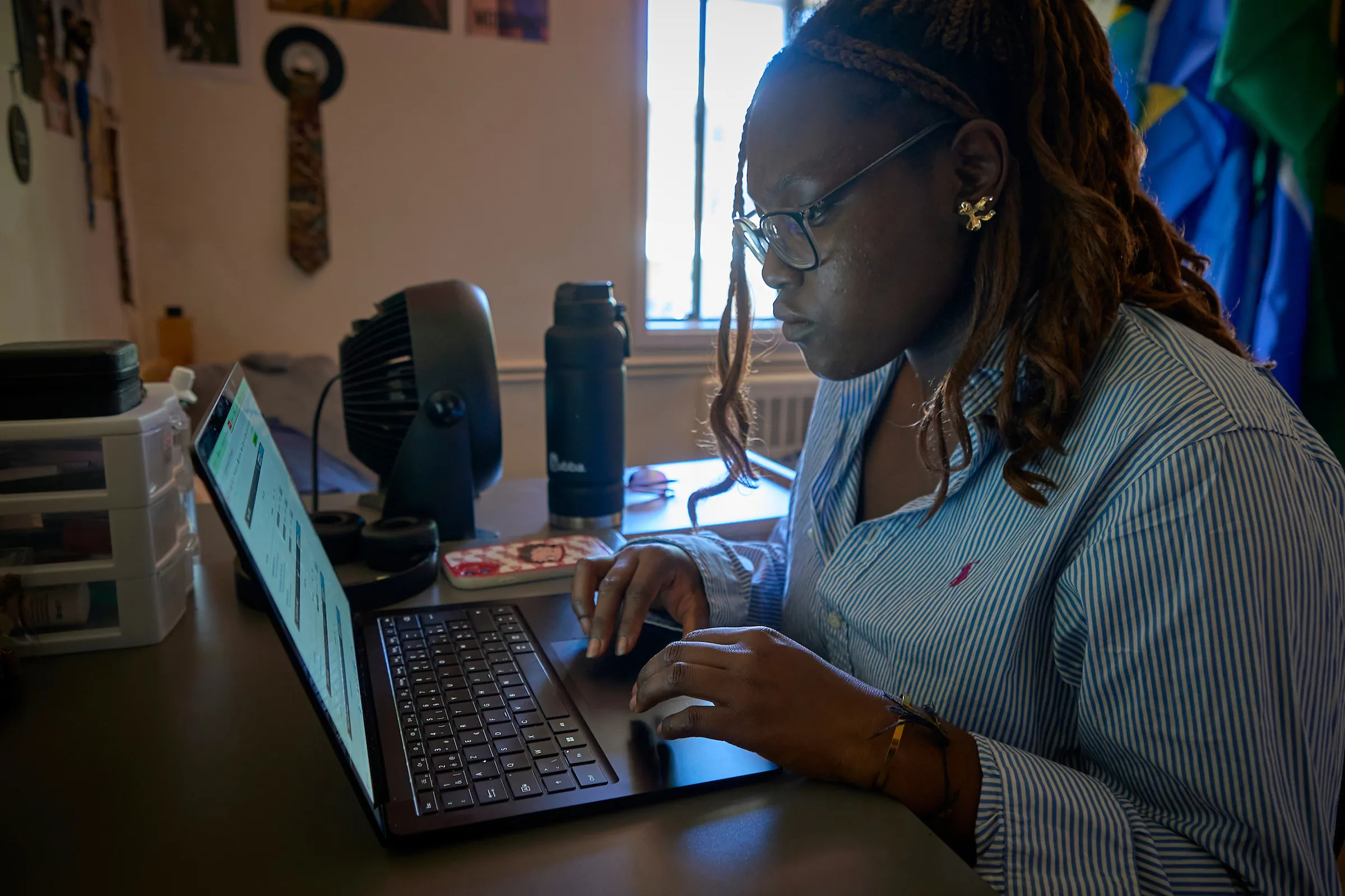 Student in her dorm room, studying and working on homework on her laptop.